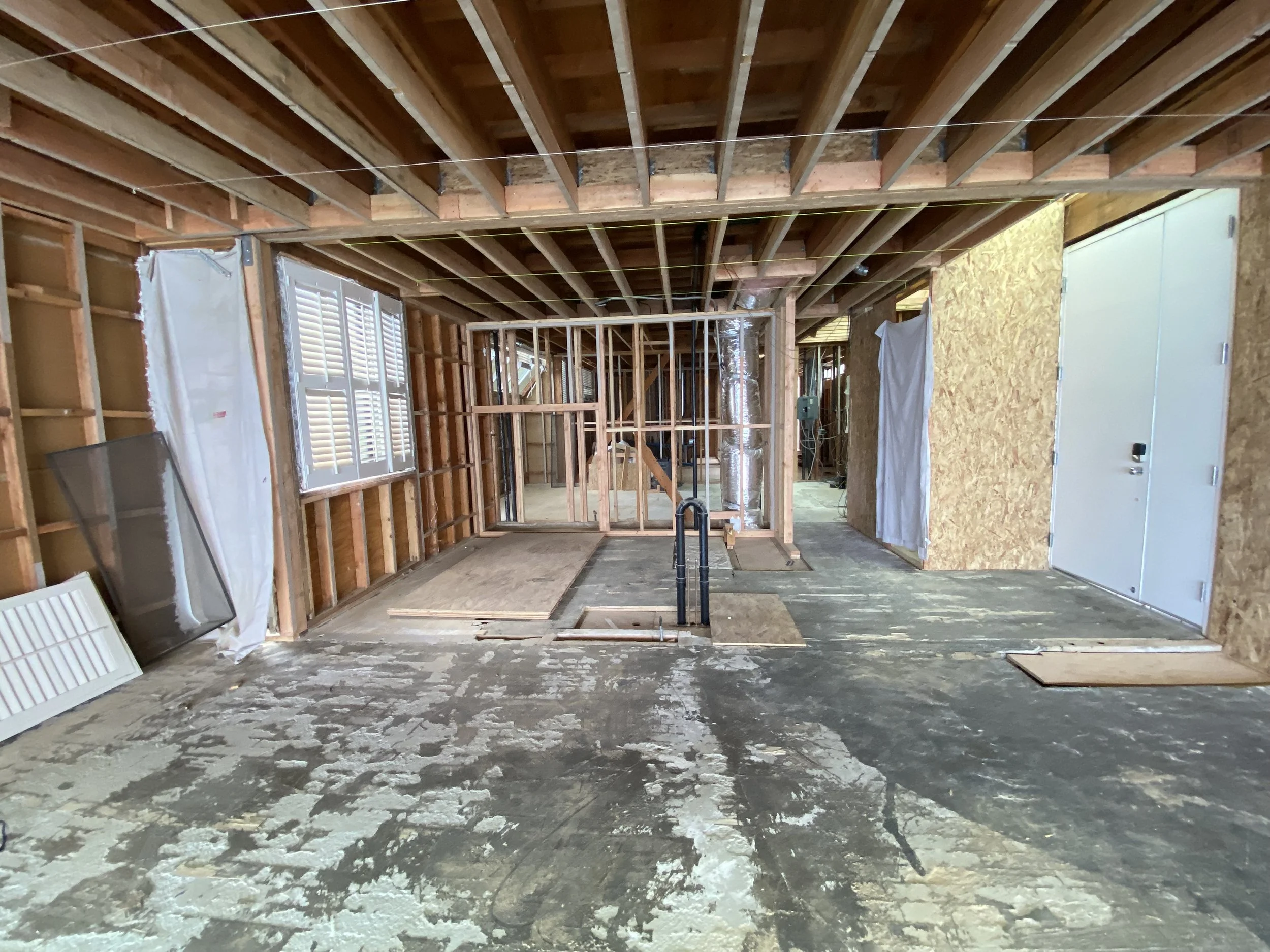 Malibu condo remodel in progress showing full gut with exposed framing, subfloor, and open layout during structural and system reconstruction
