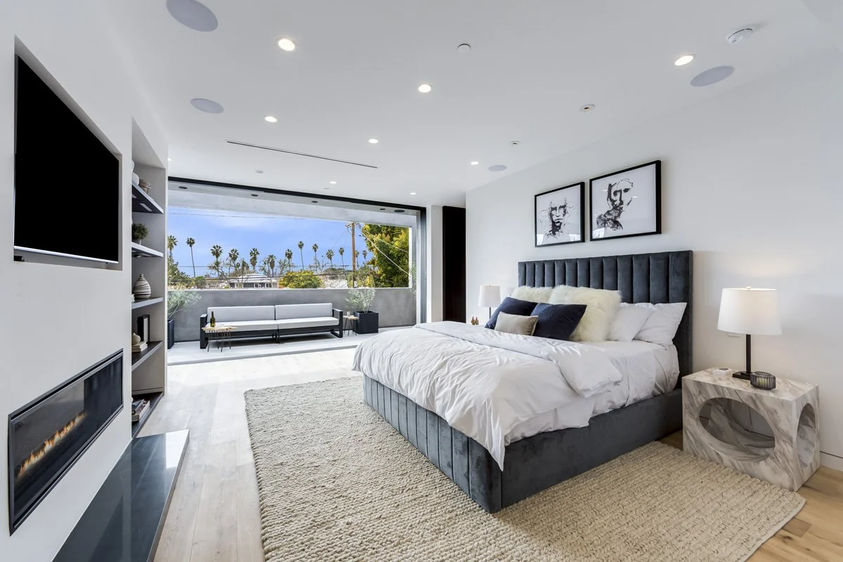 West Hollywood custom home primary bedroom with indoor-outdoor balcony and modern fireplace