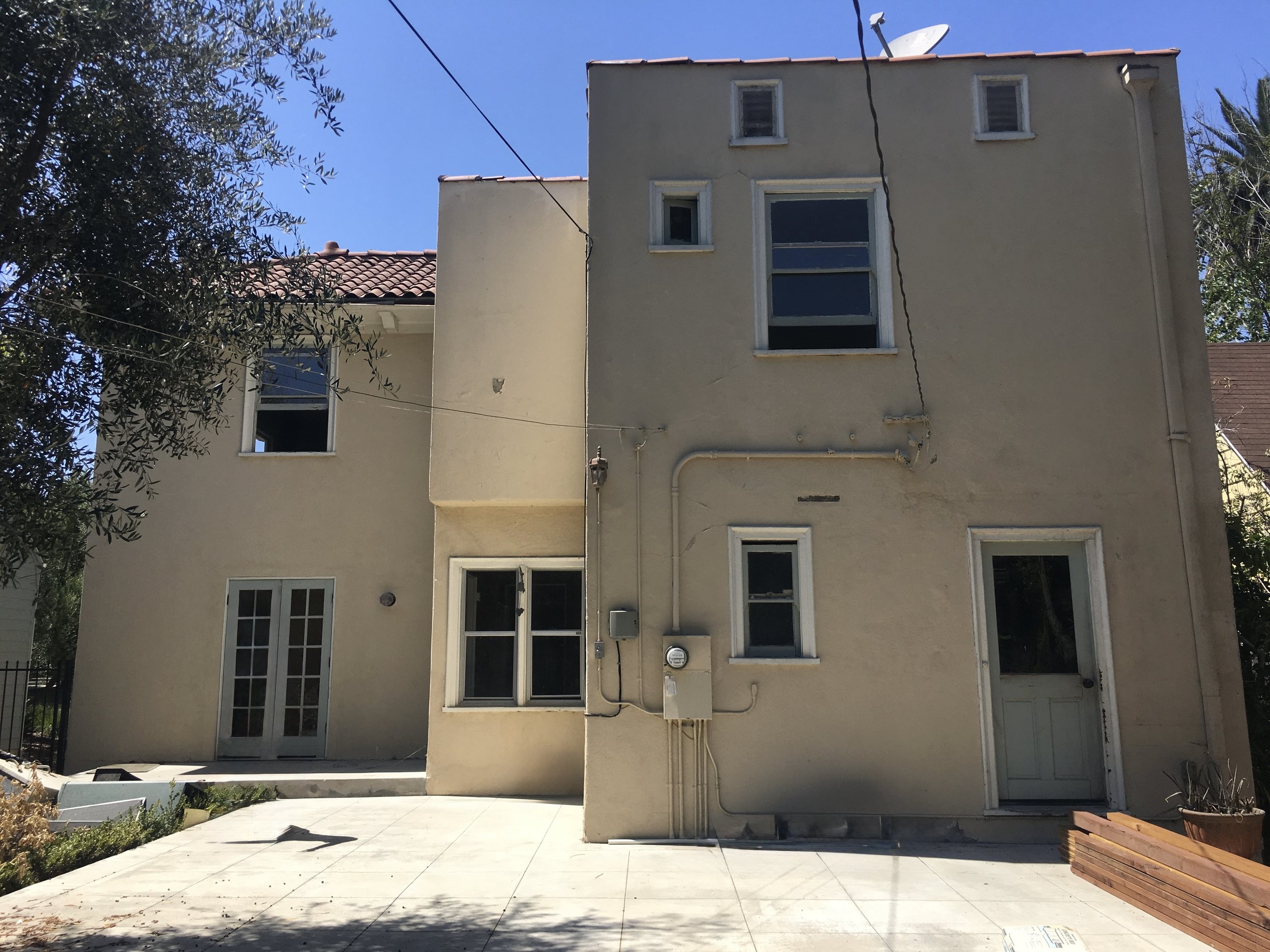 Hancock Park home before renovation rear exterior showing original layout, aging stucco façade, and limited connection to backyard