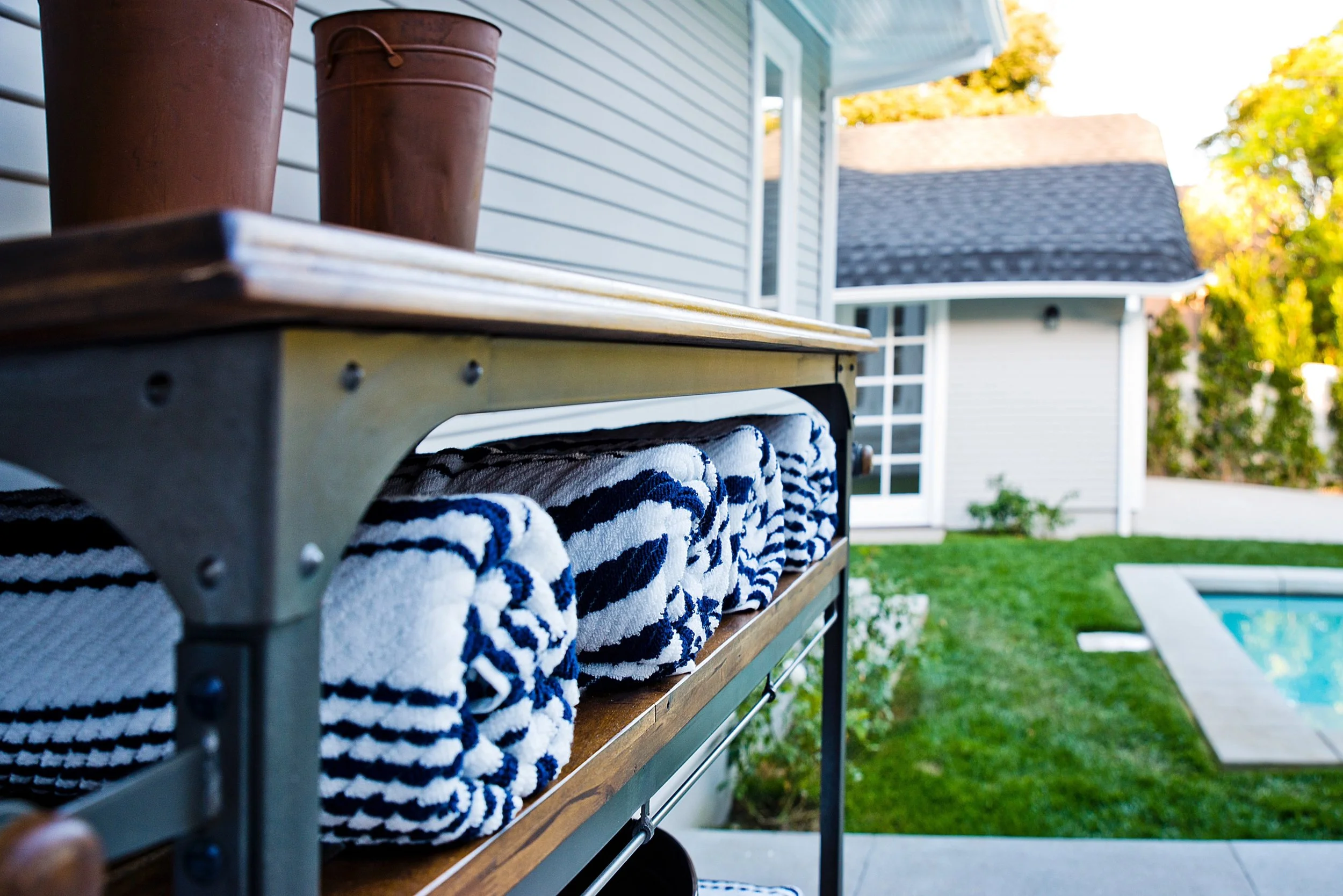 Spaulding Square custom home backyard with modern pool, manicured lawn, and outdoor towel station detail by Heart Construction in Los Angeles.