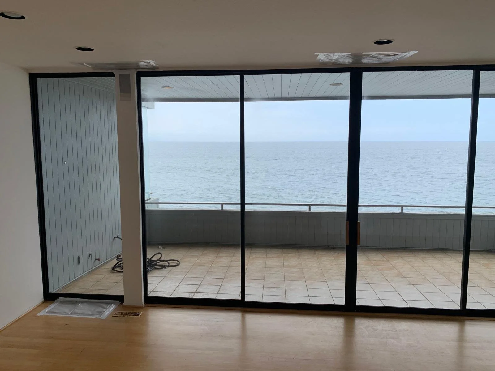 Malibu condo before renovation showing living area with sliding glass doors, tiled balcony, and ocean view that feels disconnected from the interior space