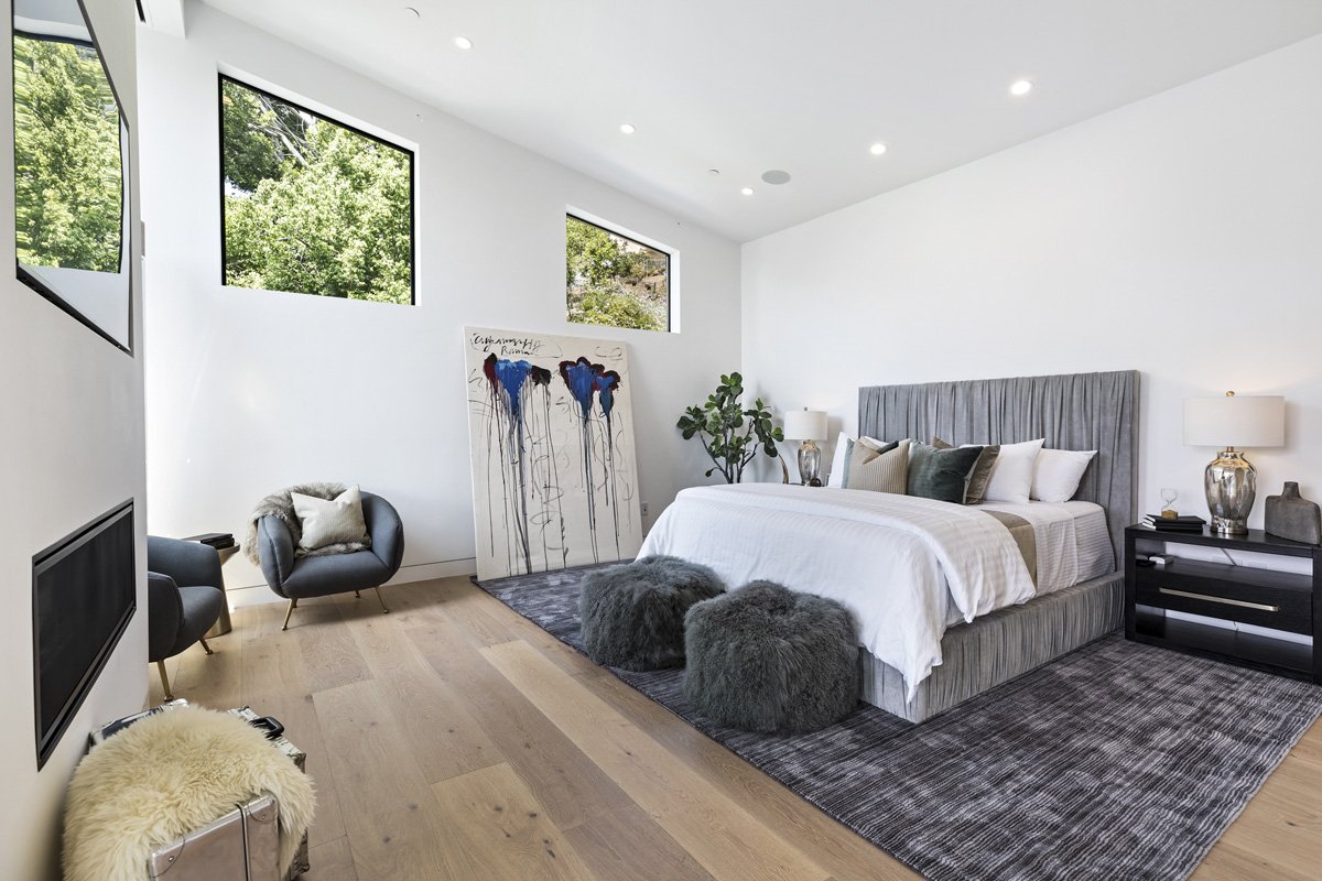 Beverly Hills primary bedroom with linear fireplace, wide-plank oak floors, and corner windows bringing in natural light