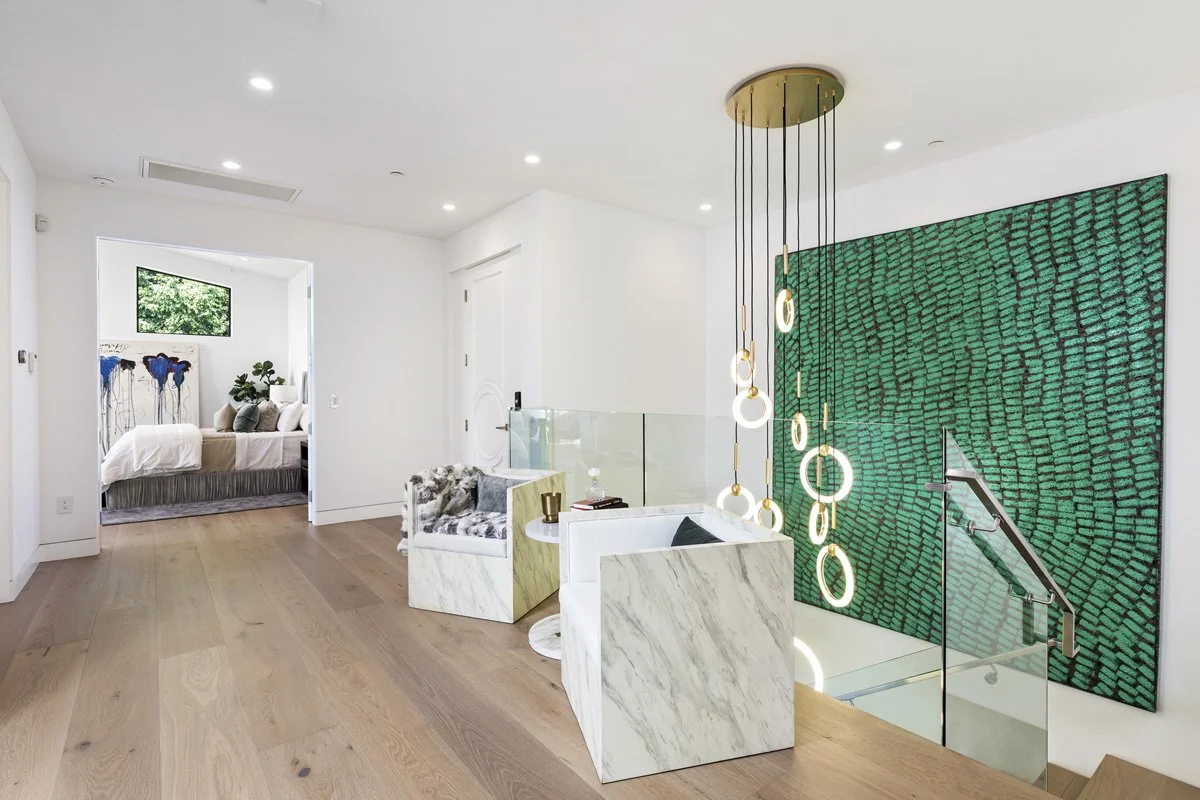 Beverly Hills upper-level lounge with glass railing, statement art wall, and sculptural pendant lighting