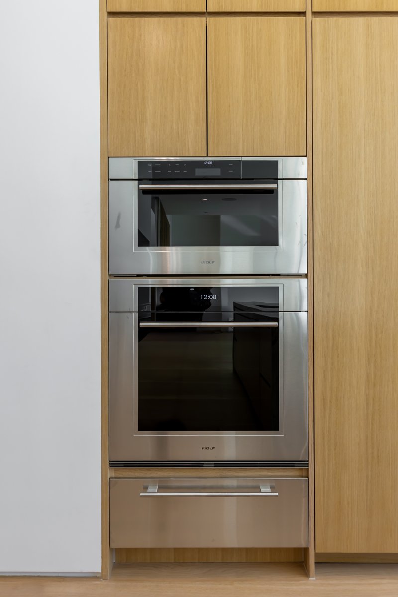 Built-in Wolf double wall ovens integrated into custom oak kitchen cabinetry in a modern Mar Vista home remodel by Heart Construction.