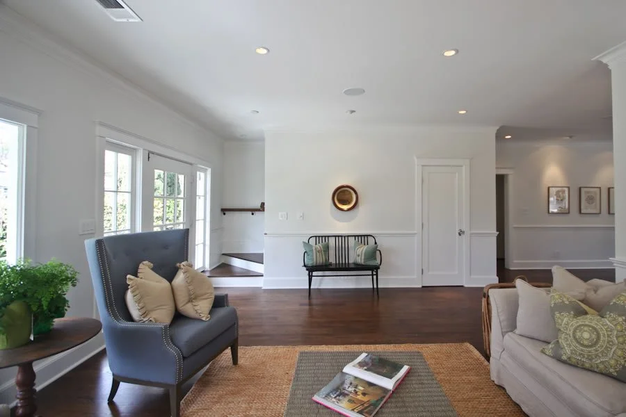 Spaulding Square custom home living room with white walls, wainscoting detail, hardwood floors, and natural light from French doors in Los Angeles.
