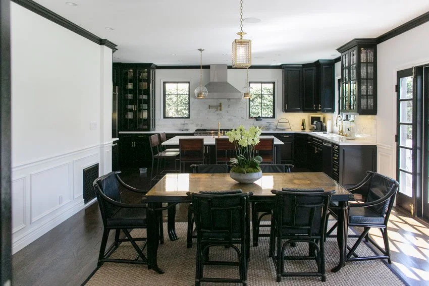 Open dining and kitchen space with marble island, black cabinetry, and French doors to backyard