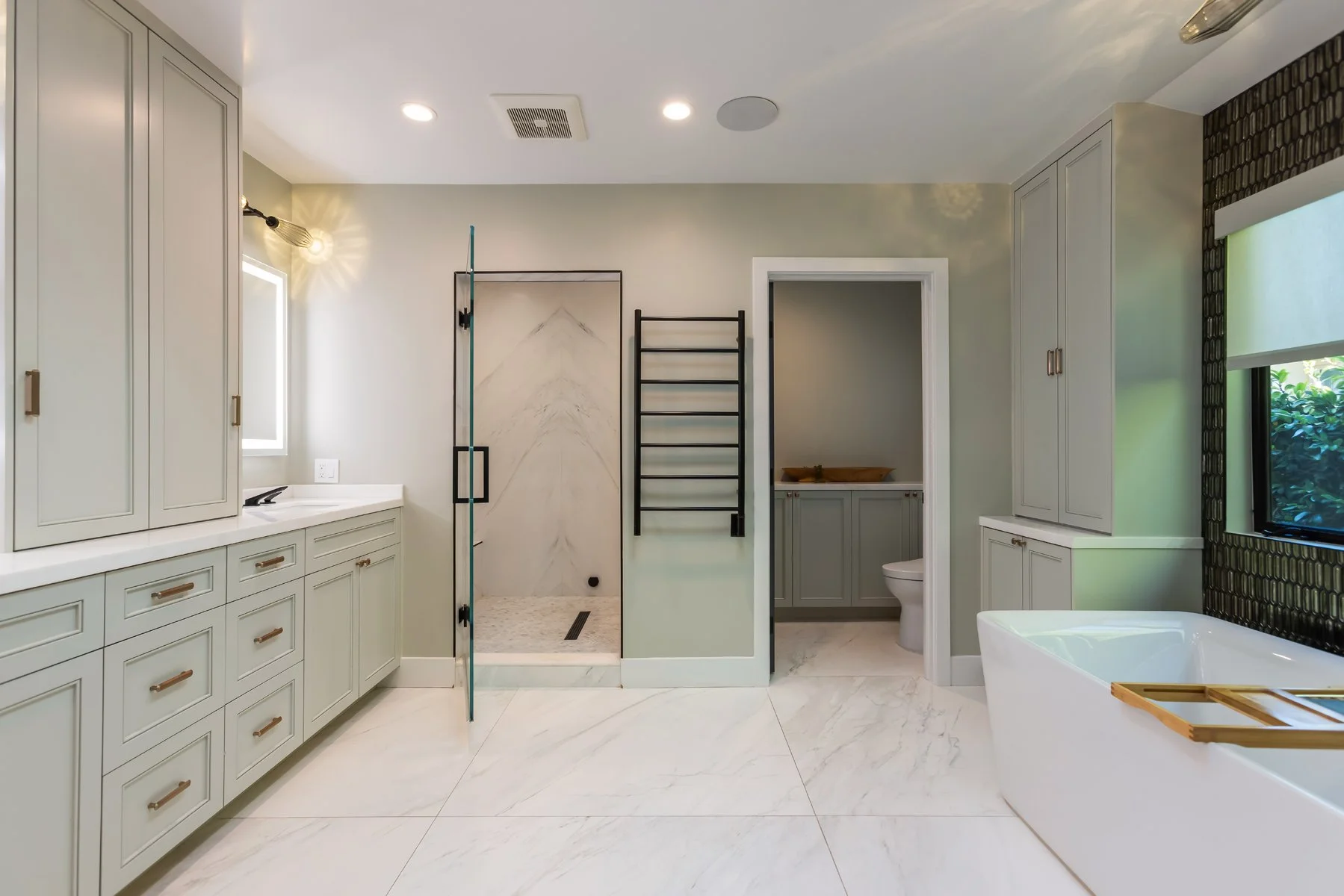 Primary bathroom remodel featuring double vanity, freestanding tub, marble tile flooring, and glass walk-in shower.