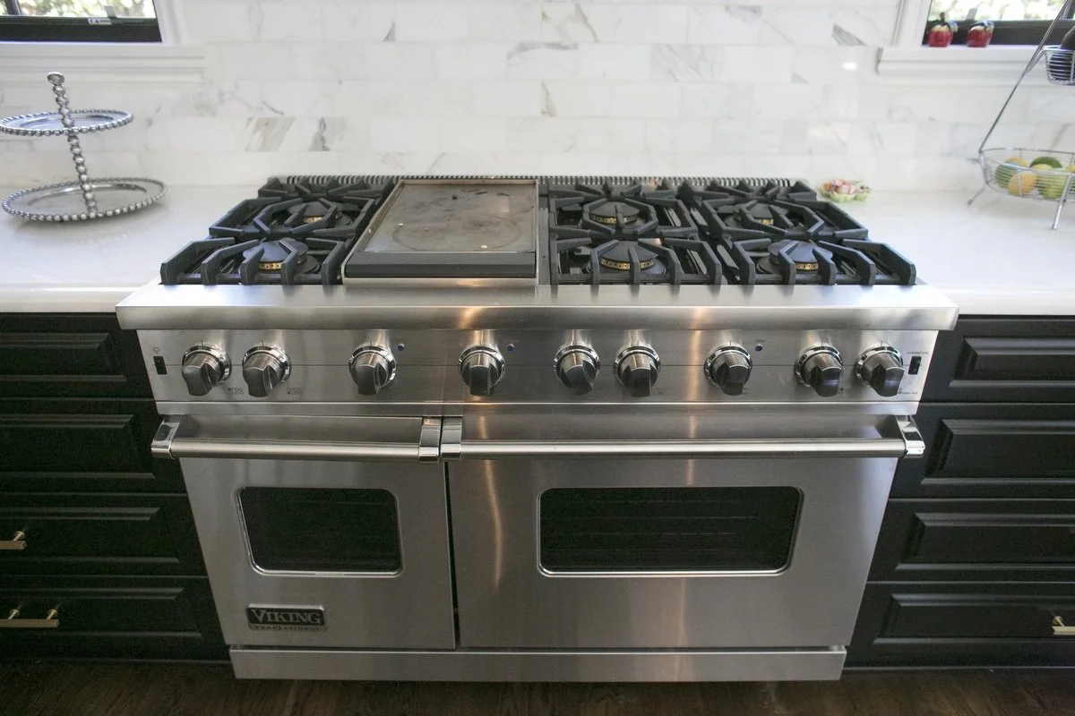 Professional Viking gas range with marble backsplash and black cabinetry in Hancock Park kitchen