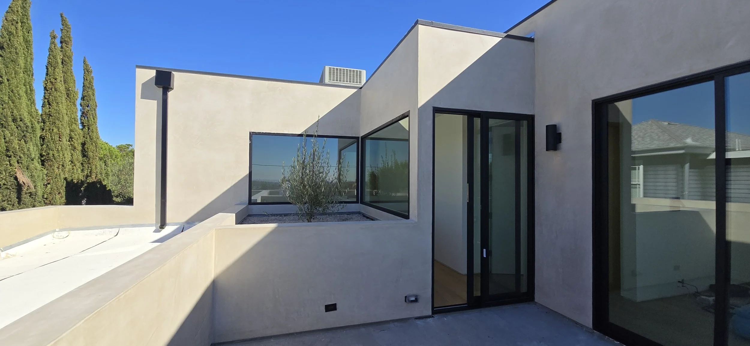 Modern custom home exterior with large corner windows, smooth stucco finish, and minimal architectural detailing