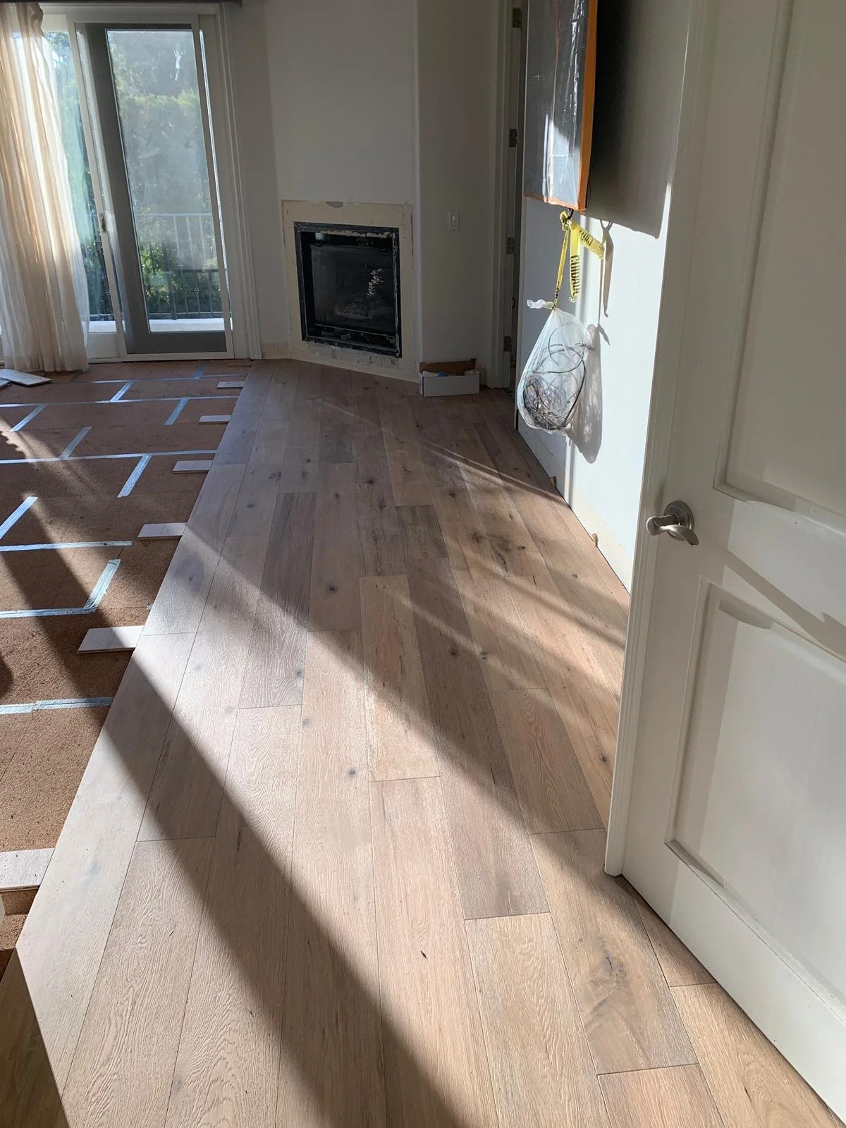 Living area of Brentwood custom home during construction with wood flooring installation and fireplace detail in progress