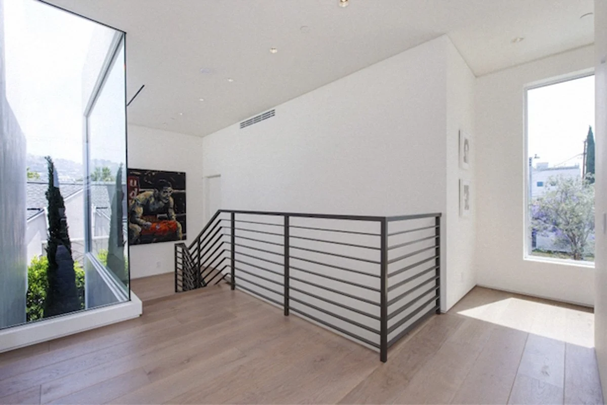 Upper level landing in West Hollywood modern home with wood floors and black steel railing.