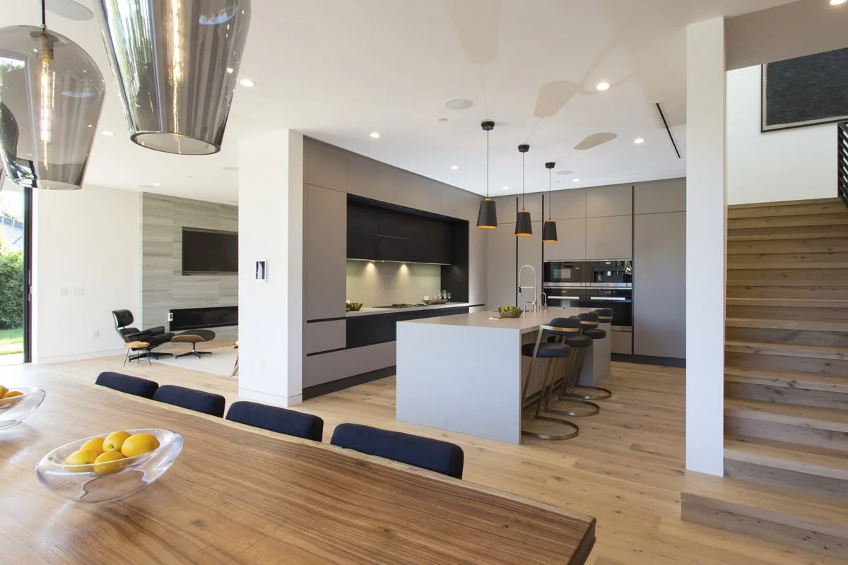 Venice contemporary open-plan living area with floating oak staircase, black steel railing, and minimalist flat-panel kitchen cabinetry