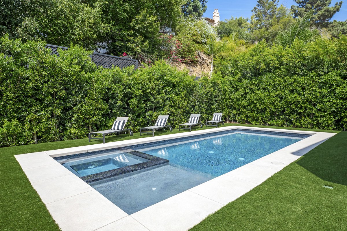 Beverly Hills backyard with rectangular pool, integrated spa, and artificial turf lawn surrounded by privacy hedges
