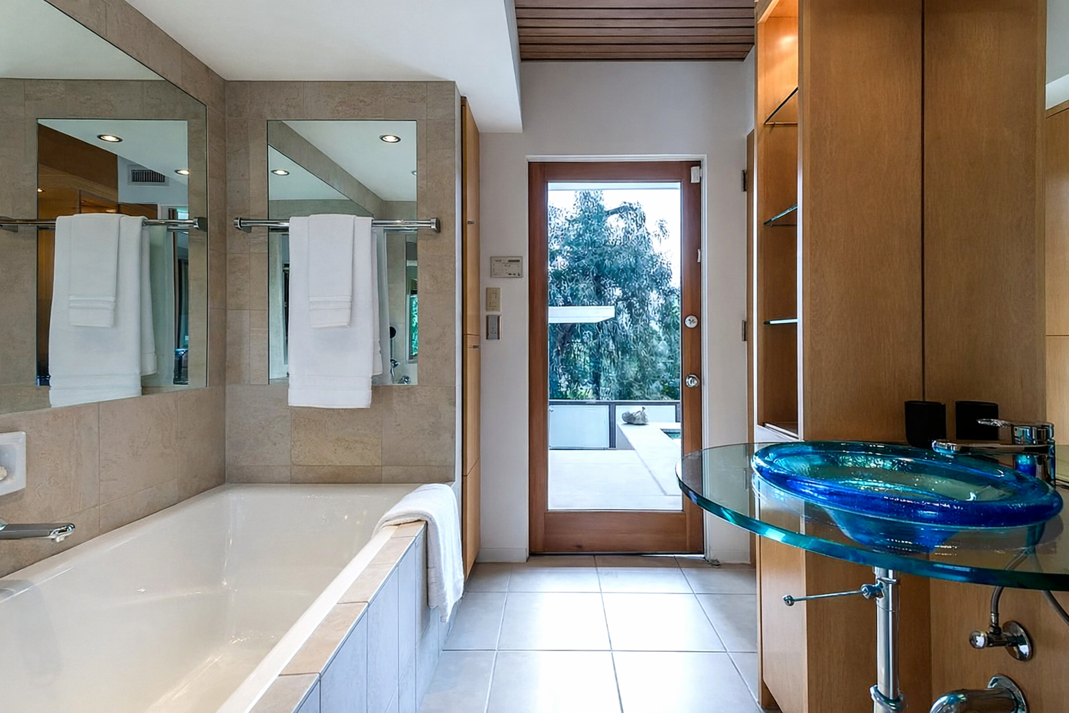 Before remodel bathroom with built-in tub, glass sink vanity, and limited connection to outdoor space in Malibu home