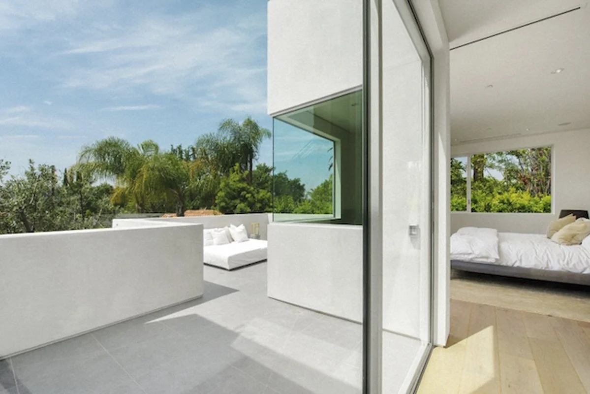 Upper terrace outside bedroom in West Hollywood custom home with large corner window and garden views.