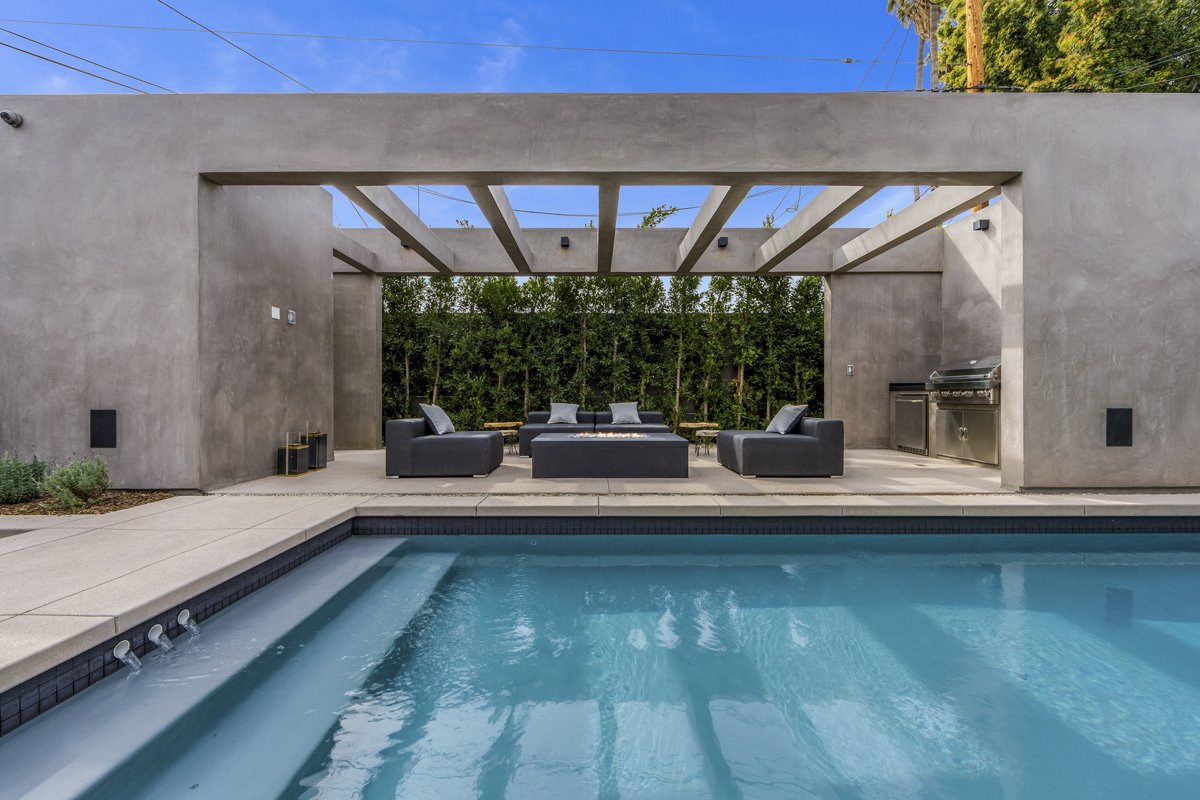 Custom outdoor living pergola in West Hollywood with built-in BBQ and poolside lounge area