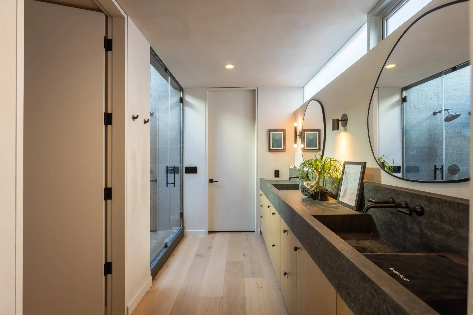 Primary bathroom remodel in Los Angeles featuring a custom double vanity with integrated concrete sinks, modern black fixtures, and glass walk-in shower.