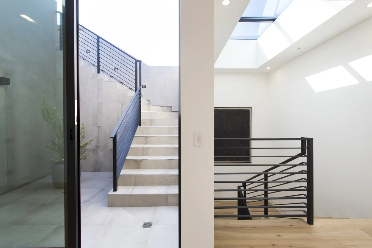 Interior staircase and skylight in contemporary Venice custom home with modern railing and natural light
