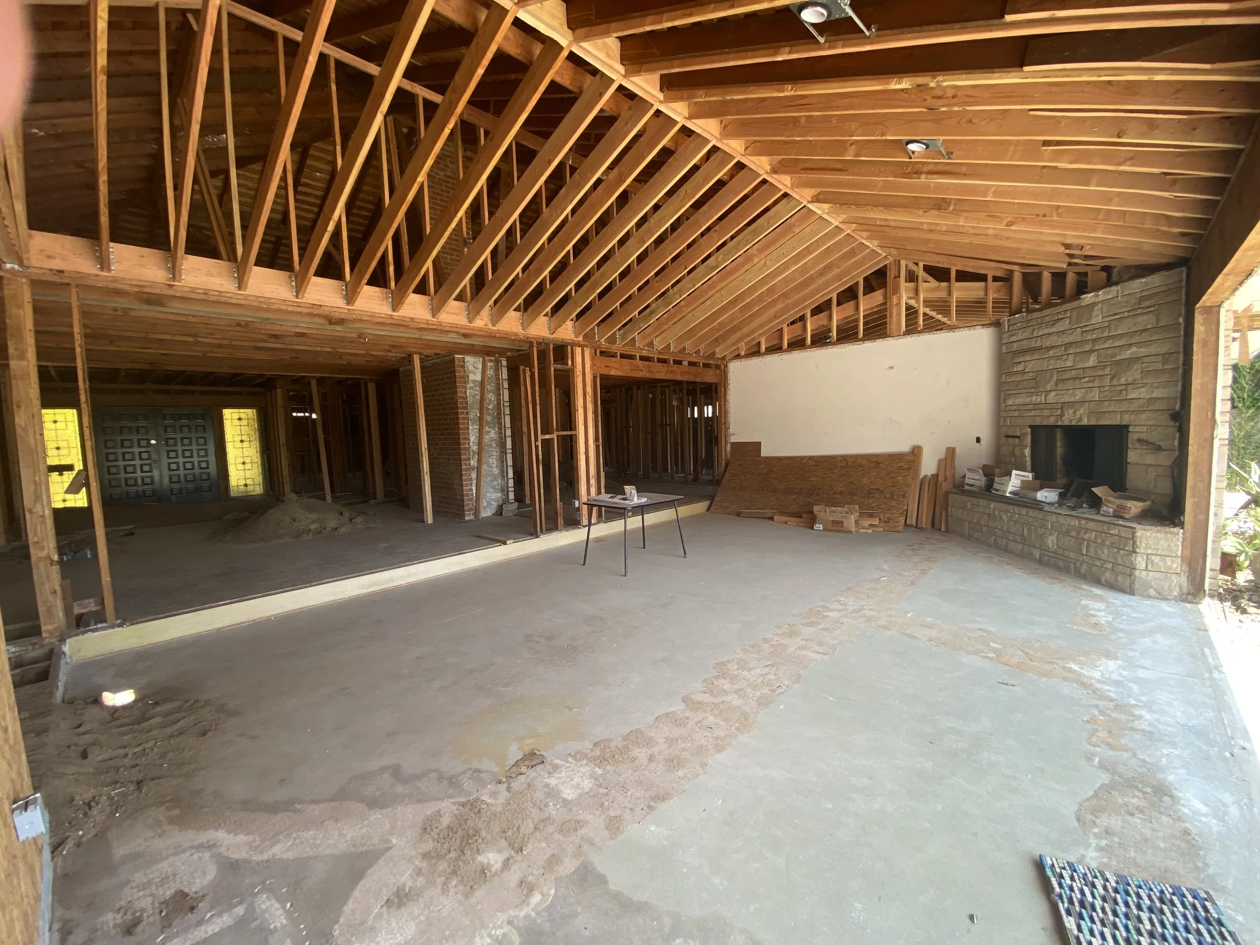 Culver City remodel in progress with vaulted framing, exposed beams, and structural reconfiguration of main living space with existing fireplace