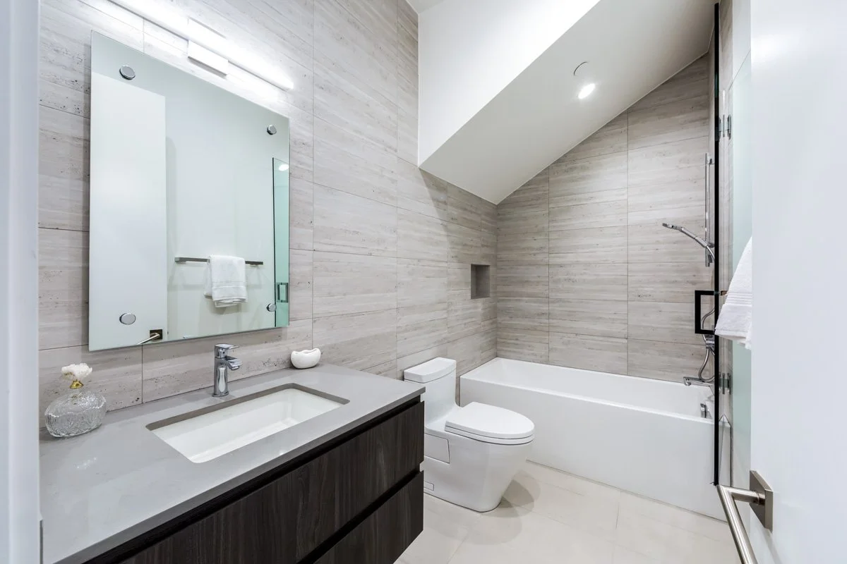 West Hollywood custom home bathroom with floating vanity, wood-look tile walls, and bathtub shower combination