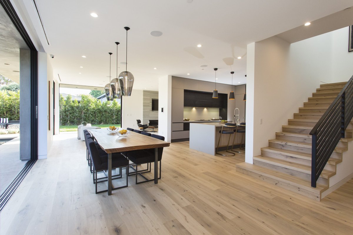 Venice modern kitchen and dining space with oversized glass pendants, custom wood dining table, and seamless backyard transition