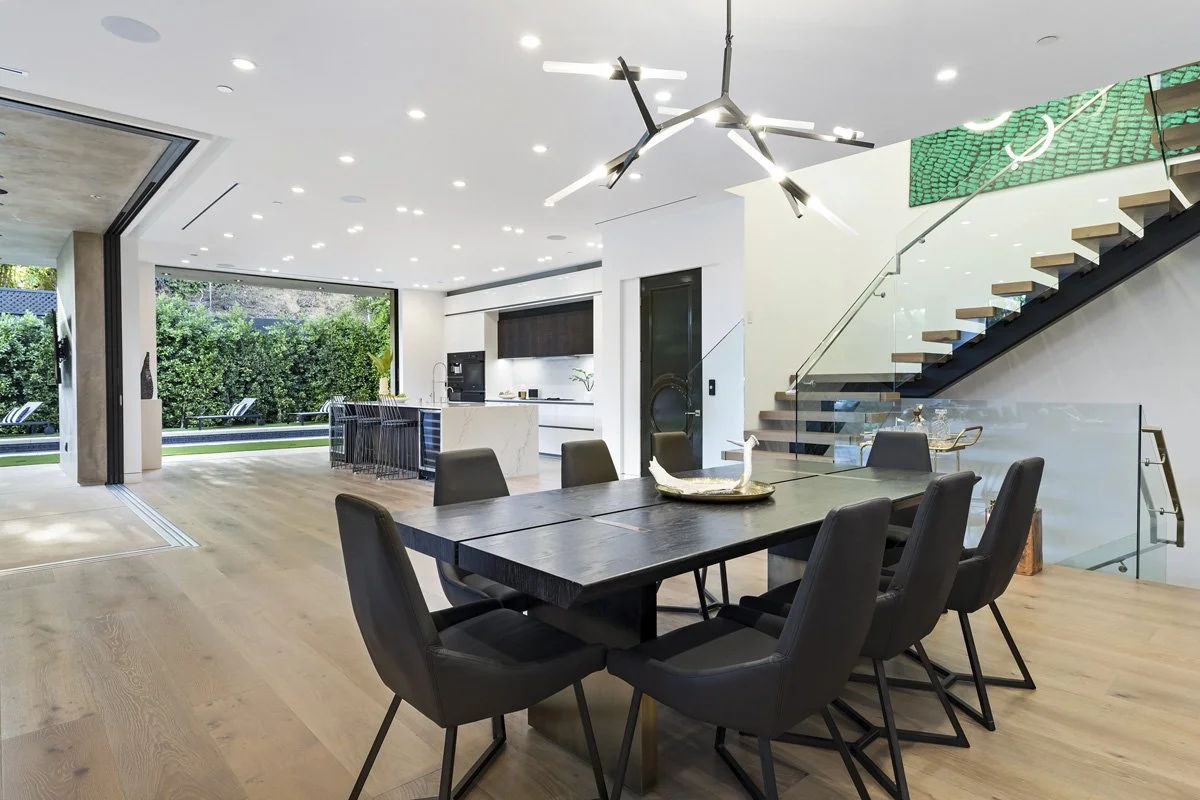Beverly Hills custom home dining area with glass staircase, modern kitchen, and indoor-outdoor connection