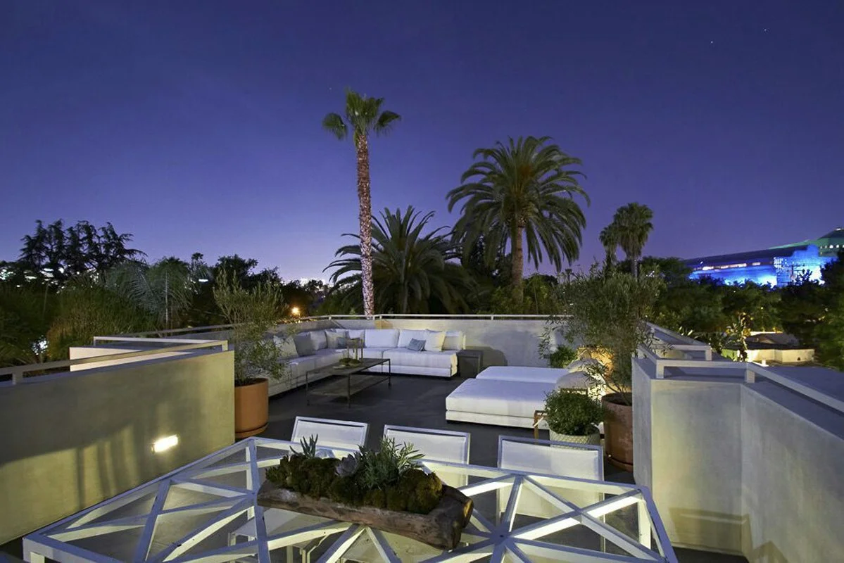 Evening rooftop lounge in West Hollywood modern home with sectional seating and palm trees.