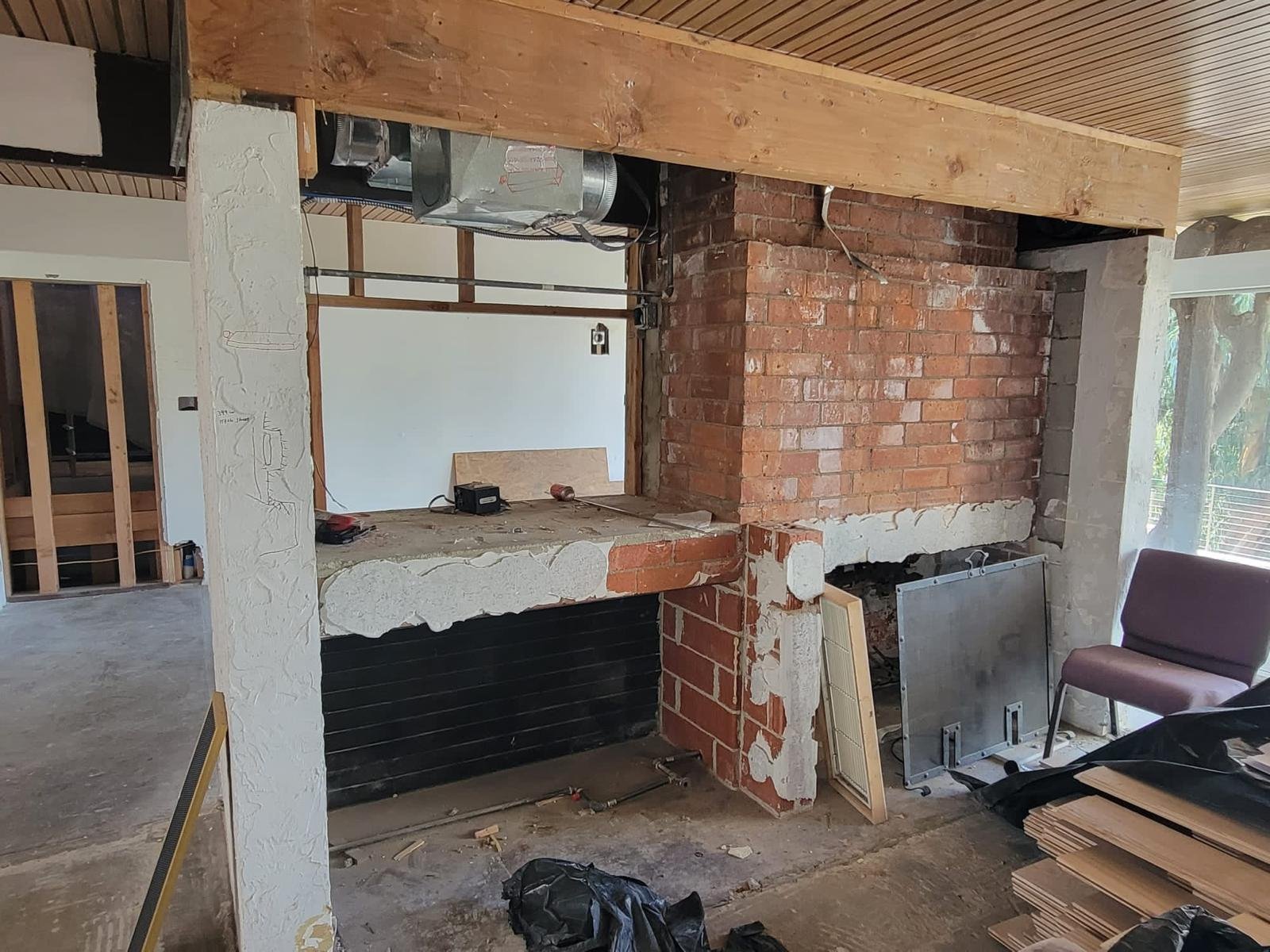 Hollywood Hills mid-century home during renovation with opened living area, exposed flooring, and large sliding doors connecting to outdoor space