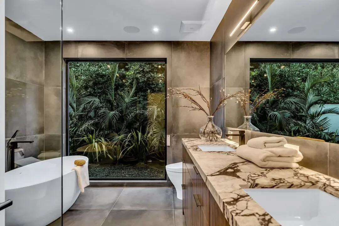 Bathroom remodel in Los Angeles showcasing a spa-inspired design with custom stone vanity, freestanding tub, and modern finishes by Heart Construction.