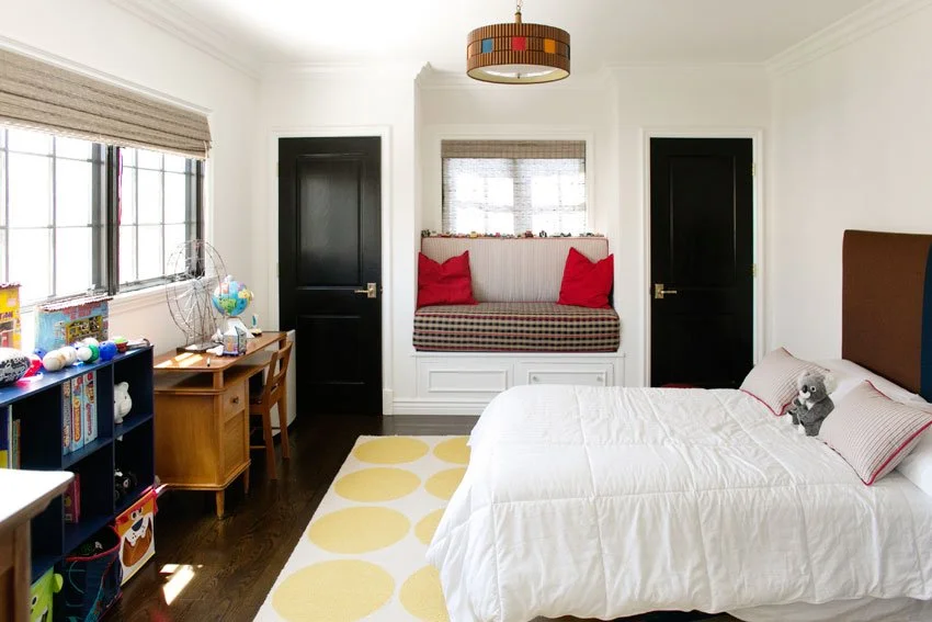 Children’s bedroom with built-in window seat, desk, and black interior doors in Hancock Park remodel