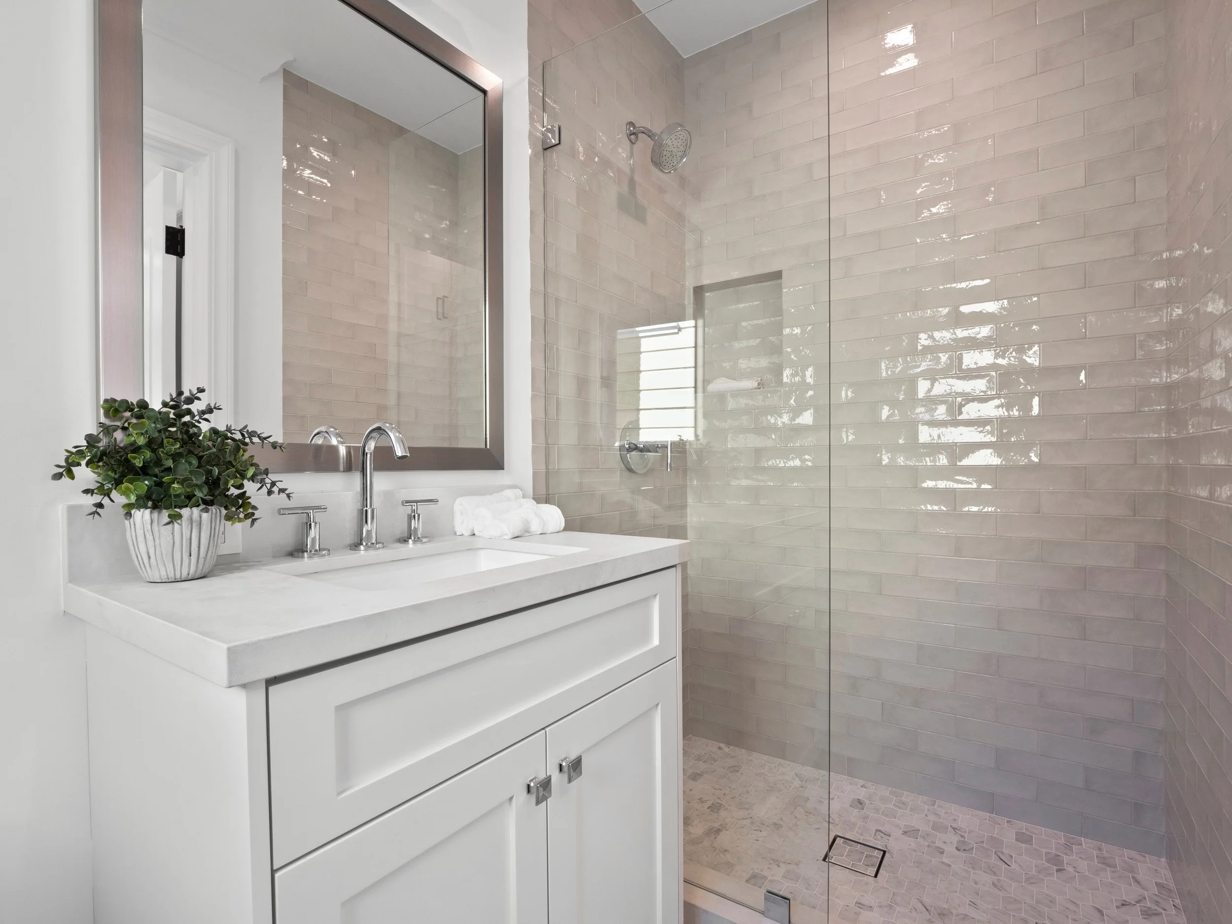 Hancock Park bathroom remodel with white shaker vanity, quartz countertop, chrome fixtures, and glass-enclosed shower with glossy subway tile and mosaic floor.