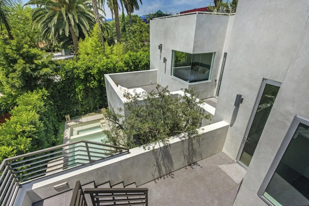 Upper courtyard terrace in West Hollywood modern residence with stair access and landscaped garden below.