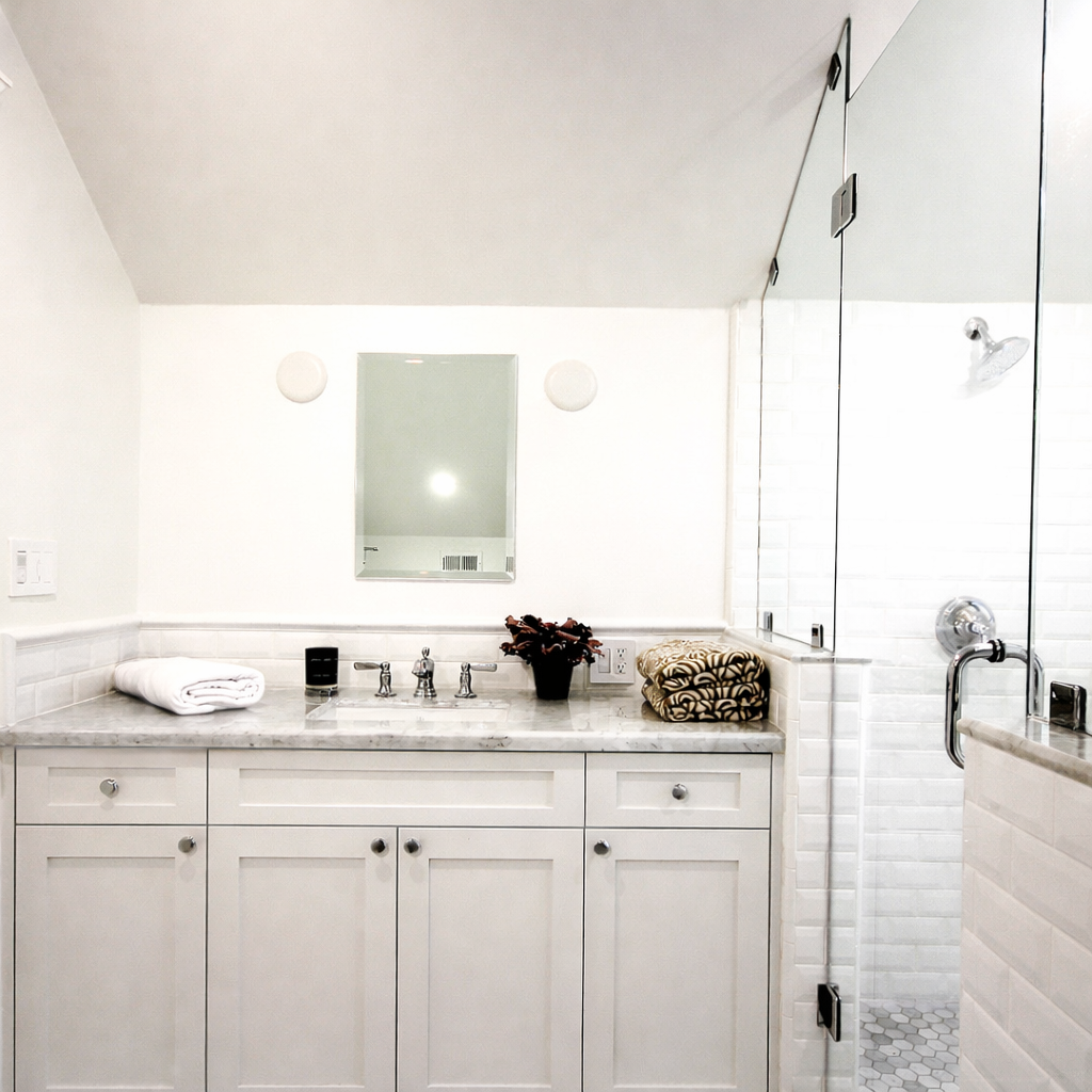 Remodeled bathroom in Spaulding Square Tudor home with marble vanity, glass shower enclosure, and chrome fixtures