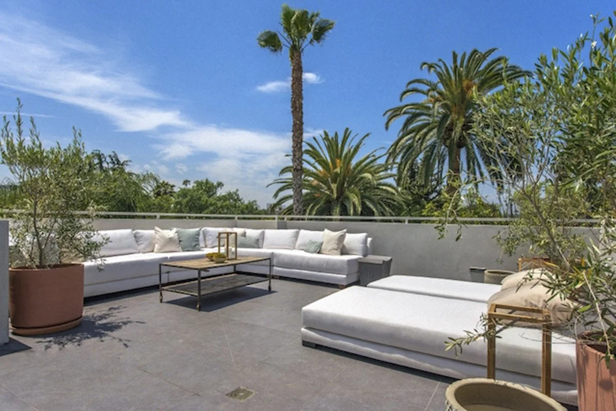 Outdoor rooftop seating area in West Hollywood custom home with palms and open sky views.