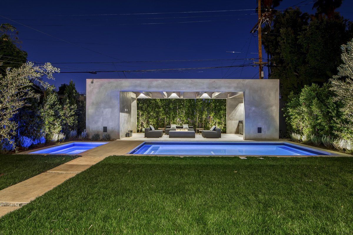 West Hollywood custom home backyard with modern pool, spa, and covered outdoor pavilion with fire feature at night