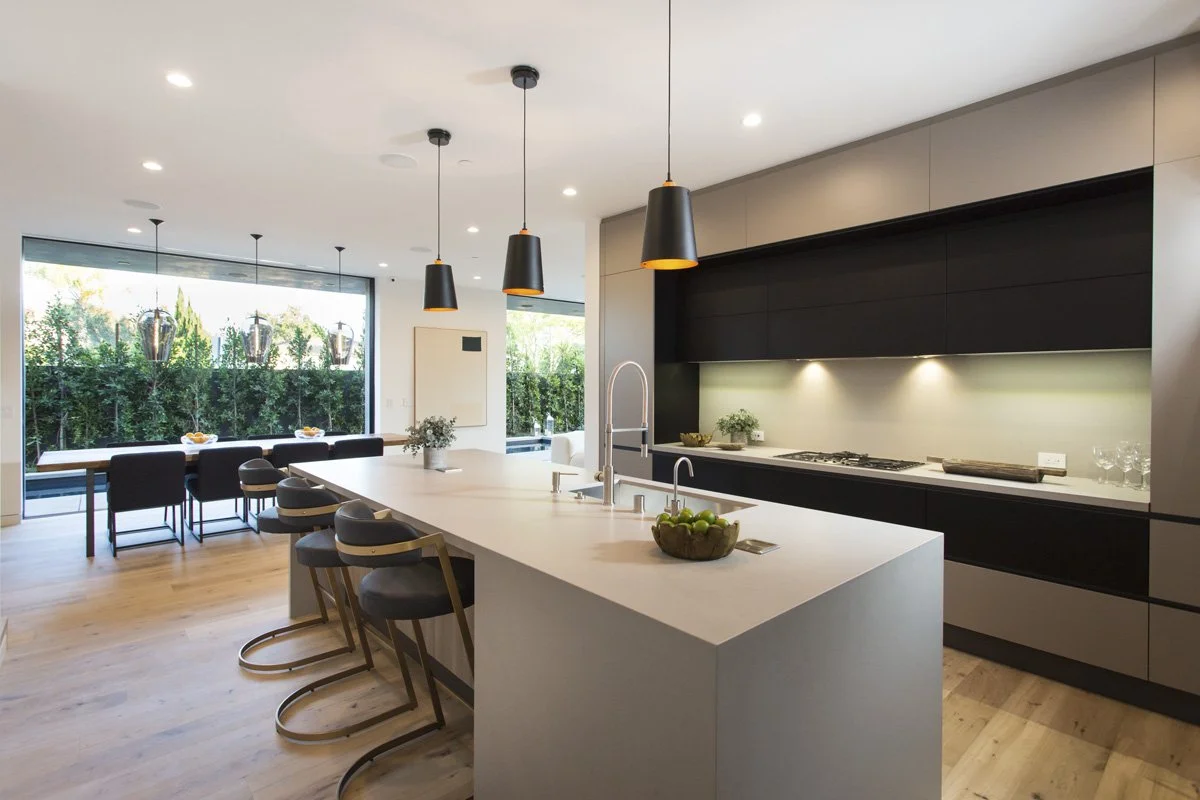 Venice contemporary kitchen and dining space with oversized waterfall island, sculptural pendant lighting, and full-height sliding glass walls