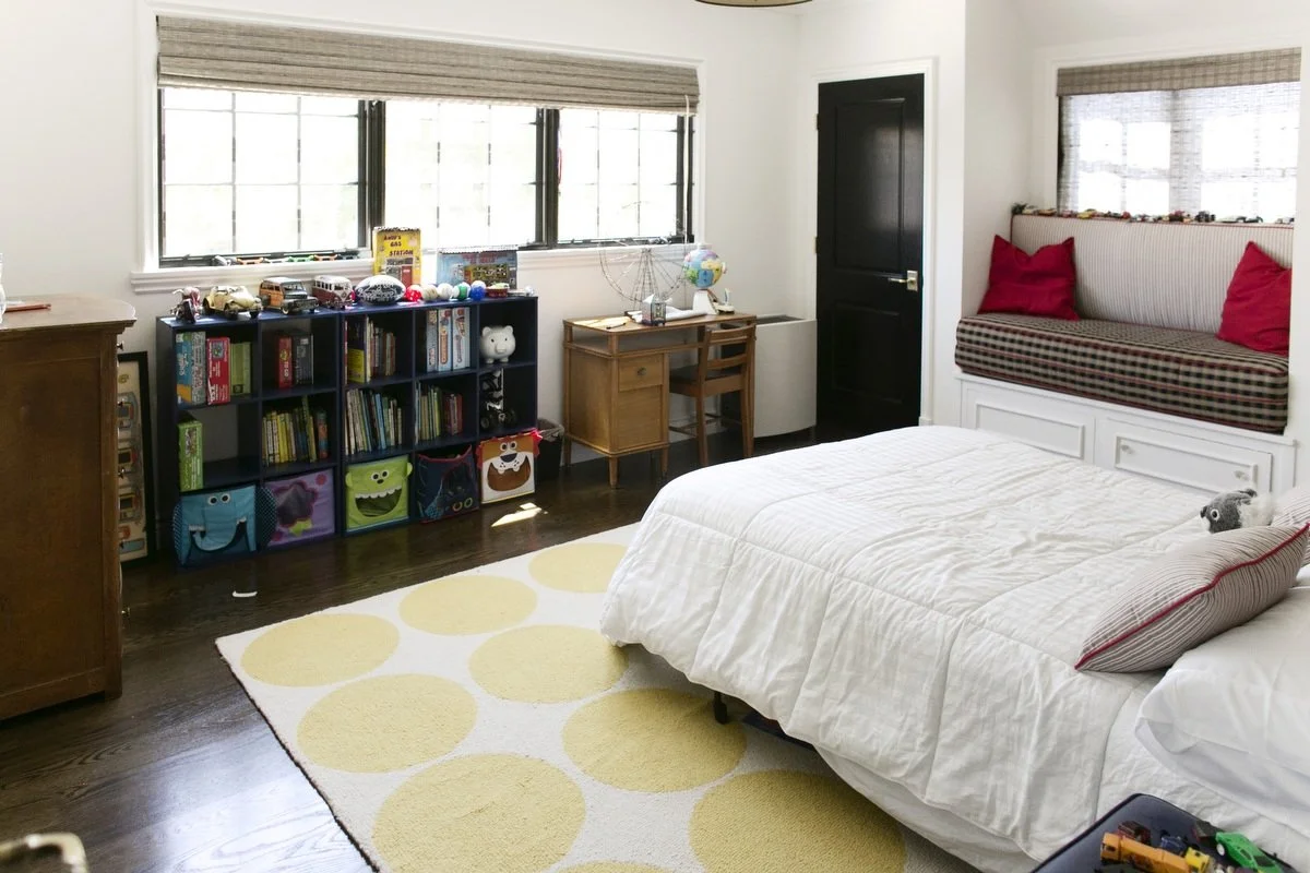 Kids bedroom with built-in bench, toy storage shelves, and large windows in Hancock Park home