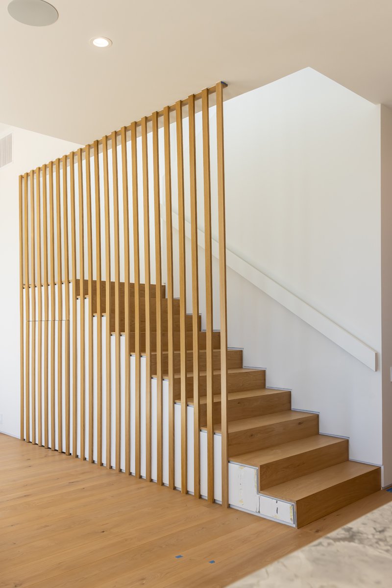 Modern Mar Vista interior staircase featuring solid wood treads, vertical oak slat screen railing, minimalist white walls, and clean contemporary detailing by Heart Construction.