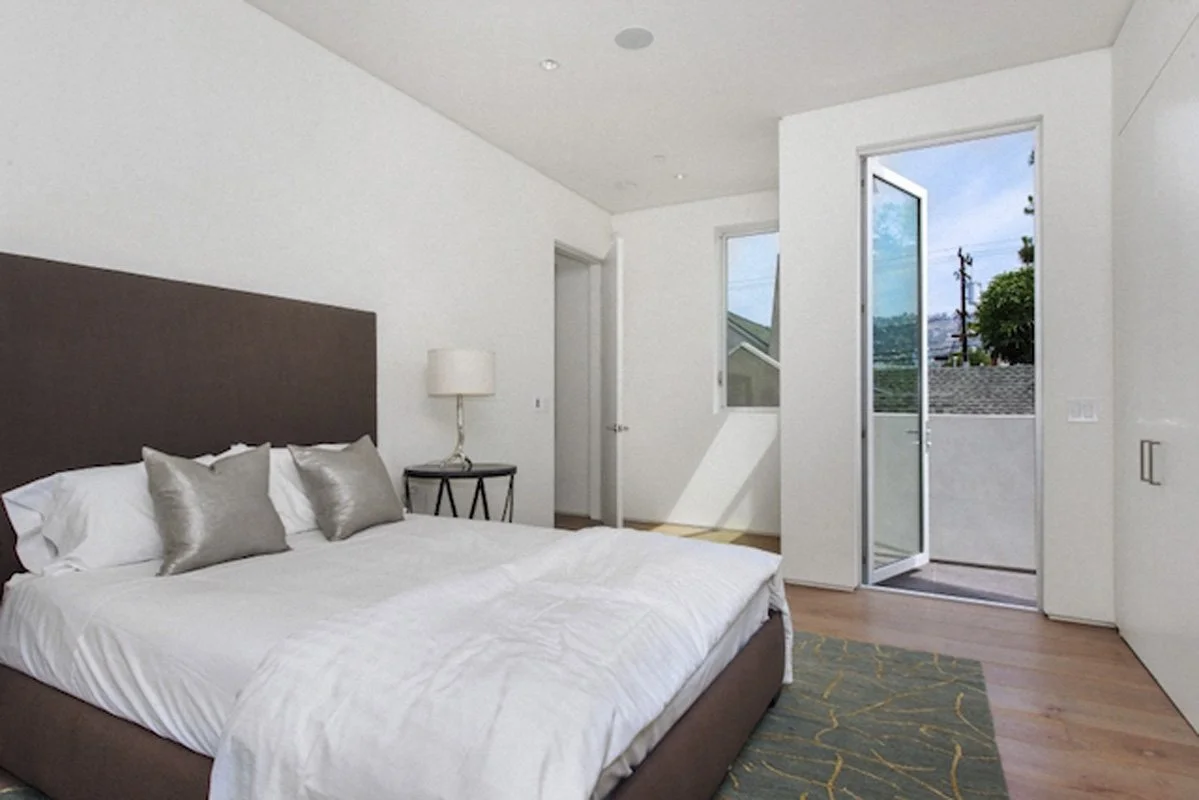 Modern bedroom with private balcony access in West Hollywood custom home with minimalist interior design.