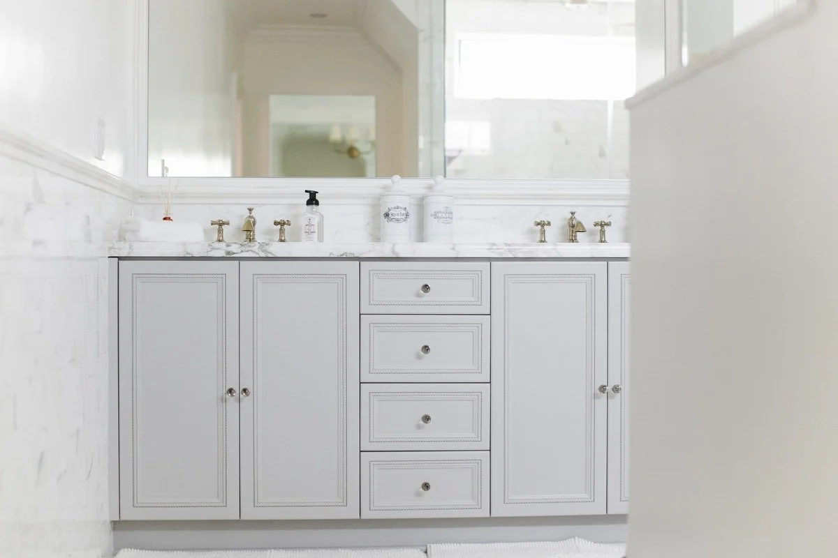 Primary bathroom vanity with white cabinetry, marble countertop, and brass fixtures in Hancock Park remodel