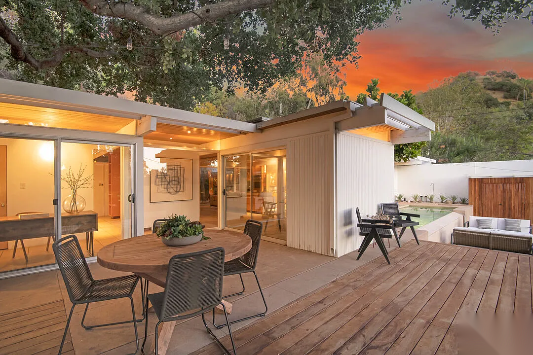 Hollywood Hills mid-century home exterior before restoration with wood deck, original sliding doors, and underutilized outdoor space with pool area