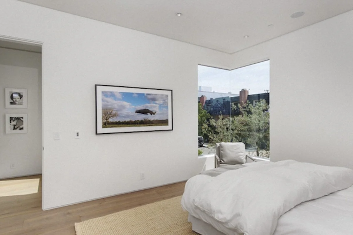 Corner bedroom in West Hollywood custom home with large picture window overlooking landscaped courtyard.