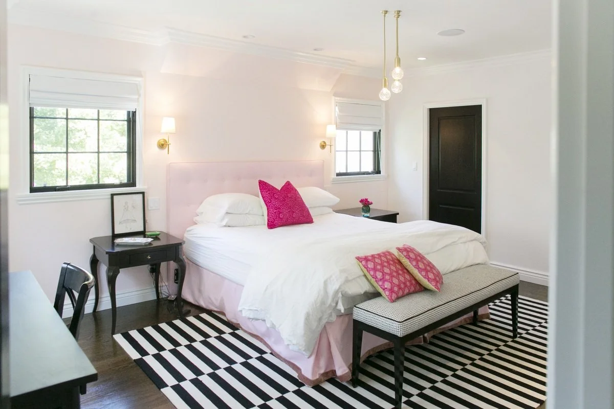 Bright bedroom with soft pink headboard, bedside tables, and large windows in Hancock Park home