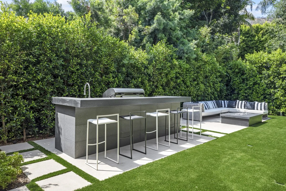 Backyard outdoor kitchen island with built-in grill and bar seating, modern outdoor living in Calabasas by Heart Construction