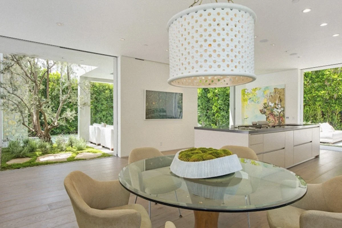 Dining area in West Hollywood custom home with round glass table and view to courtyard.