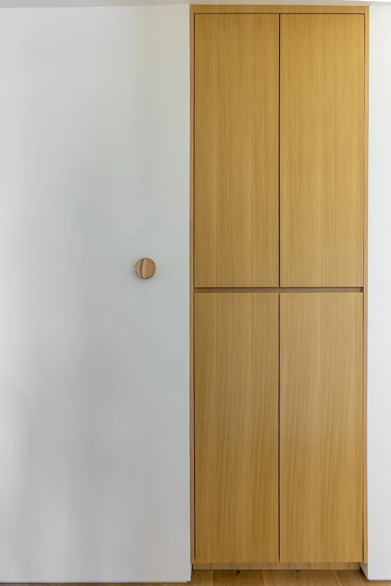 Custom Mar Vista built-in storage with flat-panel light wood cabinetry, seamless integrated pulls, and minimalist white wall detailing in a modern contemporary home.