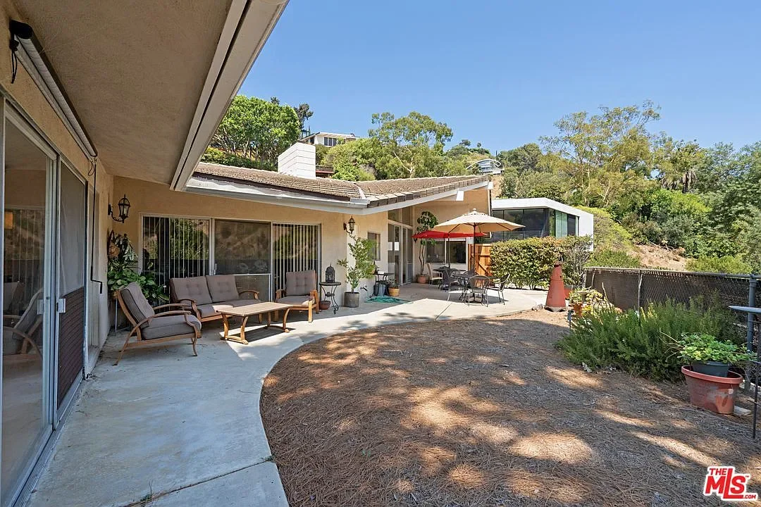 Hollywood Hills living room before remodel with stone fireplace, high ceilings, large windows, and partial connection to outdoor terrace