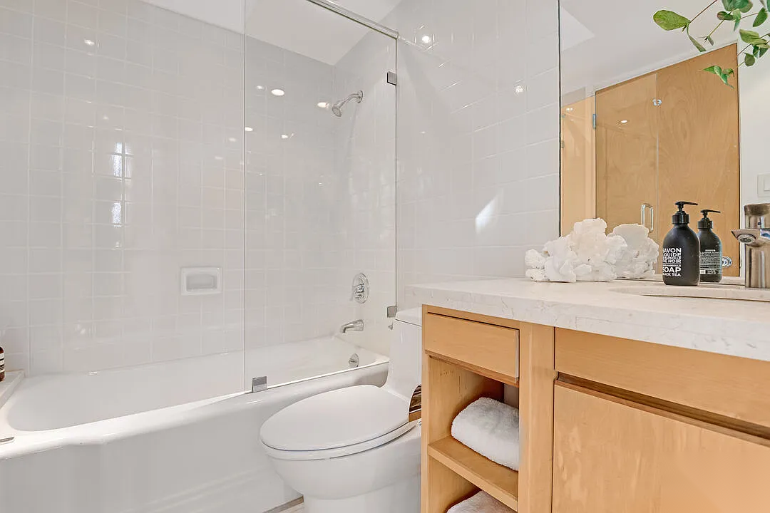 Hollywood Hills home bathroom before remodel with white tile walls, standard tub shower, and original wood vanity