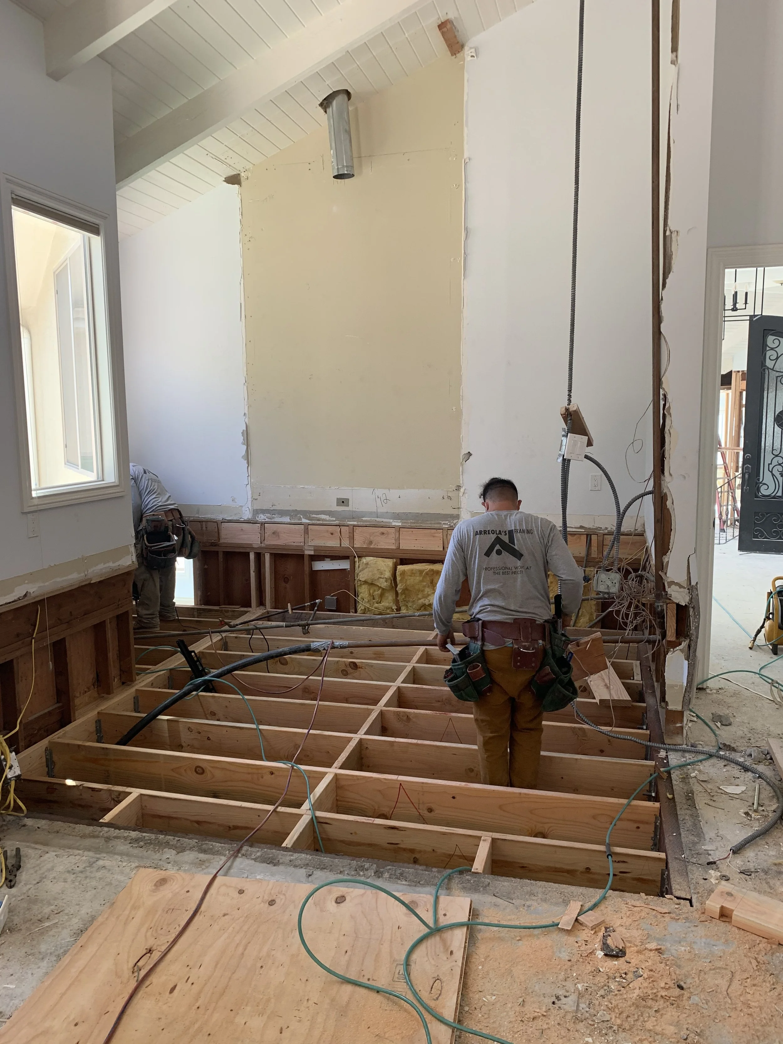 During remodel structural work with exposed floor framing and rough plumbing in Malibu home renovation