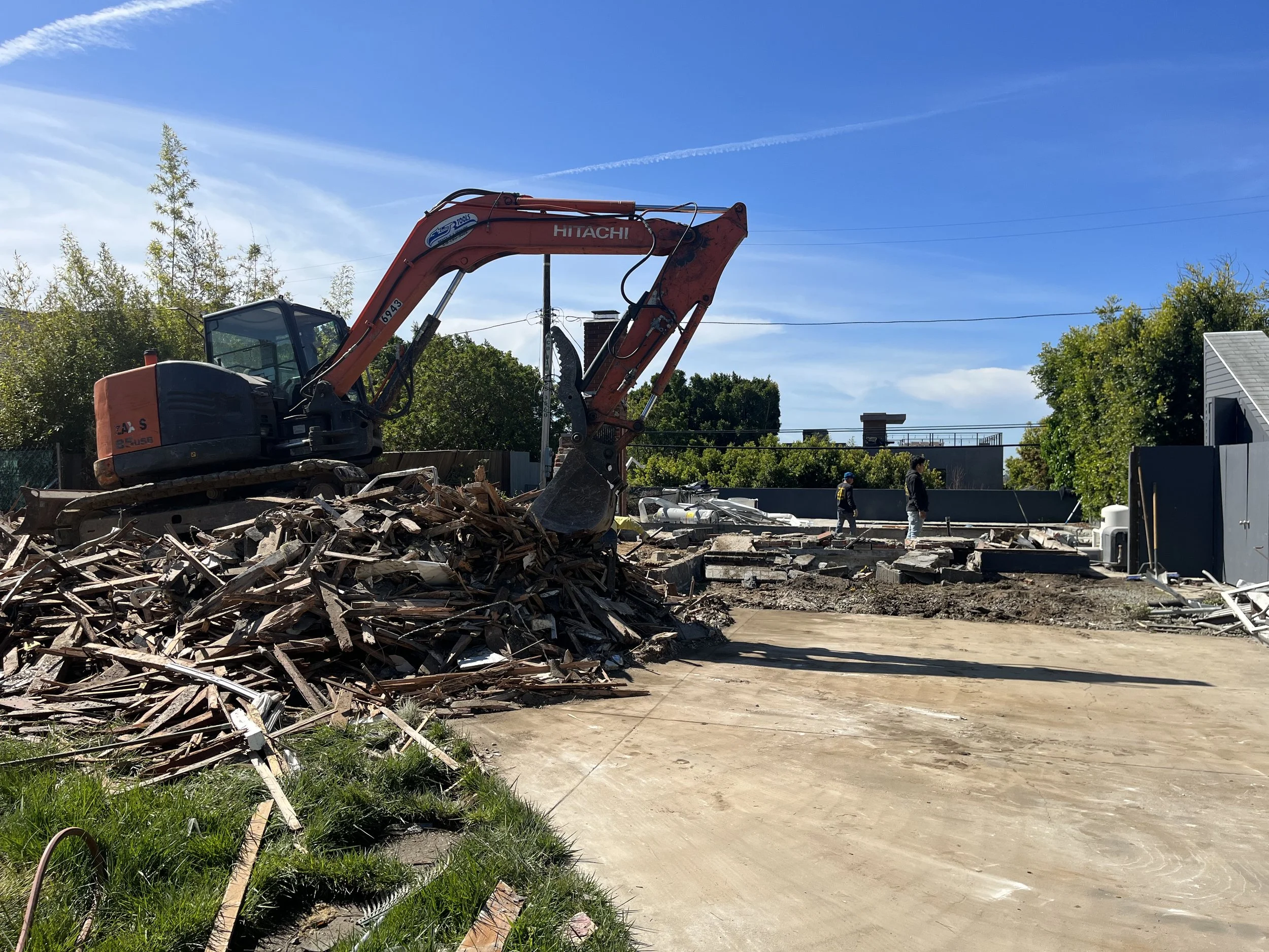 Demolition of existing home with excavator removing structure and clearing site for new construction
